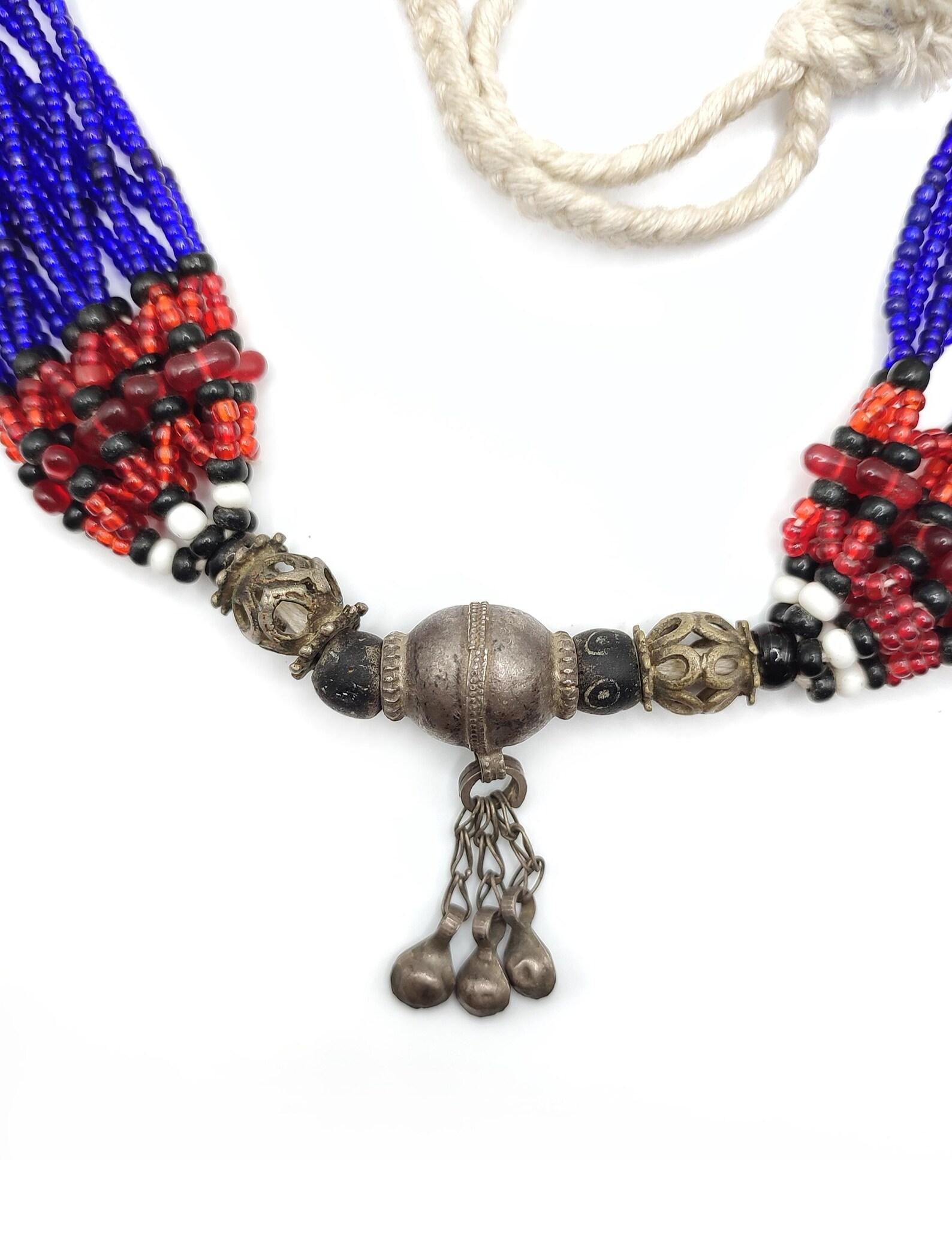 Antique ethnic beaded necklace. This colorful Afghan necklace has multiple strands and numerous small glass beads in many different colors. The central part displays three silver small pendants and silver beads.
