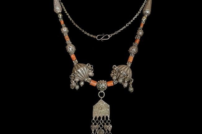Traditional Yemeni antique statement necklace featuring red, authentic coral beads, a central silver pendant and different antique silver beads.